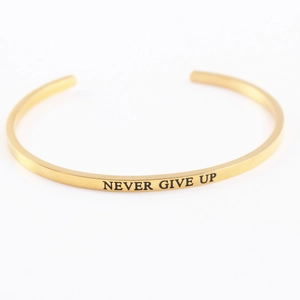 Golden stainless steel mantra bracelet with 'NEVER GIVE UP' engraved message on white background