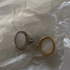 Detailed view of gold and silver oval shell rings with textured edges on paper