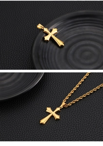 Detailed view of a gold cross pendant on a twist chain against a black leather background