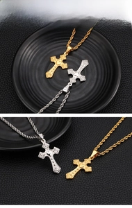 Close-up of golden and silver cross pendants with floral reliefs and rope chains
