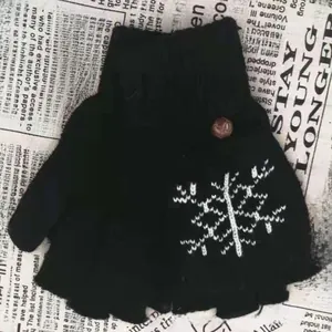 Détail d'un gant noir tricoté sans doigts avec motif flocon de neige et bouton brun