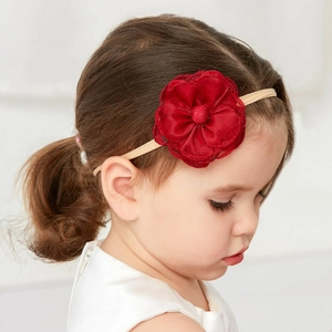 Detail of baby girl wearing a red floral headband with a soft elastic beige band