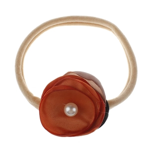 Detailed close-up of a baby headband featuring orange fabric flowers and center pearls
