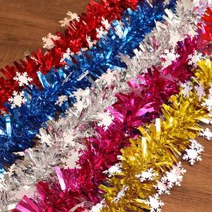 Close-up of colorful tinsel garlands with white snowflakes on rustic wooden background