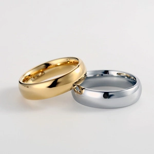 Macro view of gold and silver 6mm polished stainless steel rings on a light background