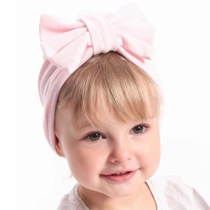 Gros plan d'un bandeau rose pour bébé avec un grand nœud en tricot sur un modèle