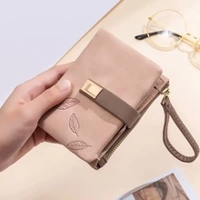 Close-up of nude pink leather card holder with leaf embossing and a wrist strap