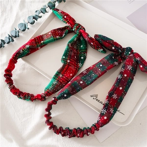 Close-up of knotted Christmas headbands featuring festive red and green plaid snowflake patterns