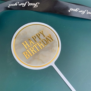 Acrylic happy birthday cake topper with marble texture and gold letters for party decor.