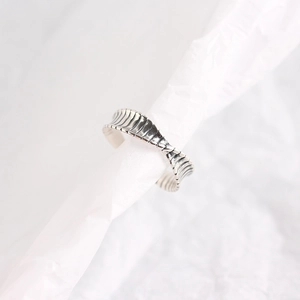 Detailed close-up of S925 sterling silver mobius ring with textured wave design on paper