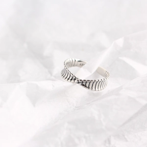 Macro detail of S925 sterling silver Mobius twist ring with hallmark on white textured paper