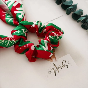 Detail of Christmas scrunchie with red green ribbon and white snowflake pattern texture