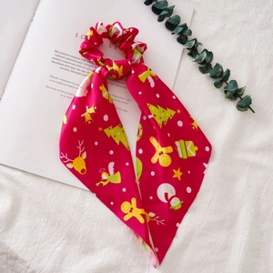 Close-up of red Christmas scrunchie with gingerbread and reindeer patterns on a magazine