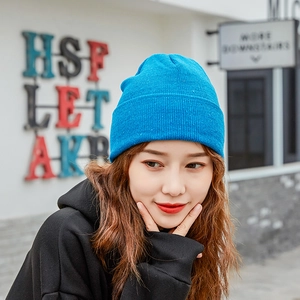 Blue knit beanie hat with cuff worn by a model in a trendy outdoor setting
