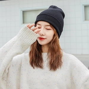Close-up of a soft black knitted beanie worn by a model in soft natural sunlight
