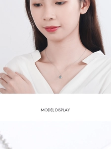 Detailed view of a blue planet Saturn pendant necklace worn on a model collarbone