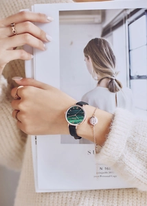 Detail of green malachite dial watch with black leather strap and golden 'M' bracelet