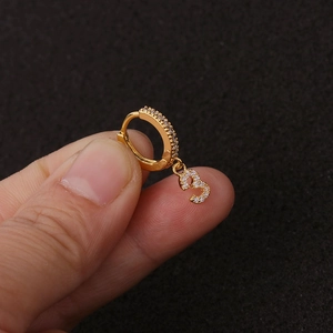Detail eines goldfarbenen Ohrrings mit Zirkonia-Nummer-3-Anhänger, von Hand gehalten