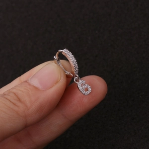 Detail eines silbernen Huggie-Ohrrings mit glitzerndem Zirkonia-Anhänger Nummer 6