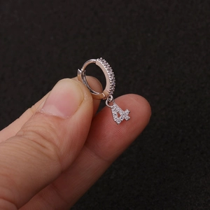Nahaufnahme eines silbernen Huggie-Ohrrings mit einem Zirkonia-Anhänger in Form der 4