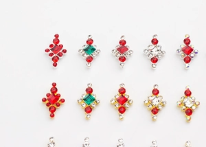 Détail macro de charmes de bijoux d'ongles en strass rouge et vert avec bases or et argent
