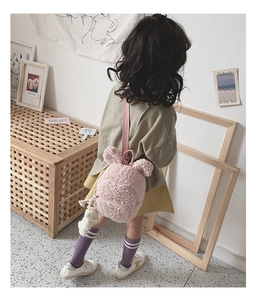 Gros plan du sac à dos en laine d'agneau rose avec oreilles d'ours et peluche blanche