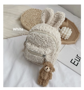Détail d'un sac à dos blanc en laine d'agneau avec oreilles de lapin et pendentif ours