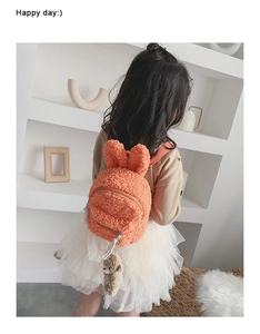Détail du sac à dos en laine d'agneau orange avec oreilles de lapin et breloque ours