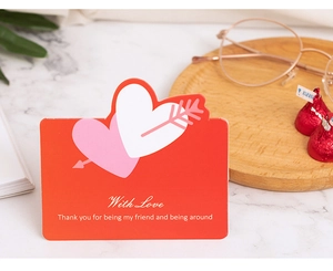 Gros plan d'une carte de vœux rouge avec motifs de cœurs et texte With Love sur marbre