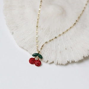 Detailed view of cherry pendant necklace with red crystals on a white coral base