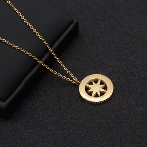 Detail of gold compass pendant showing the intricate 8-pointed star on a matte black base