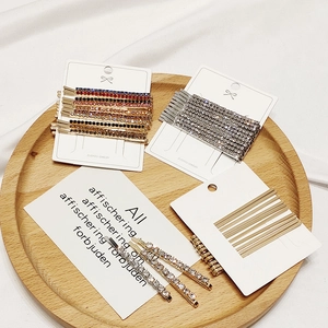 Set of assorted alloy rhinestone hairpins in gold and silver on a wooden tray