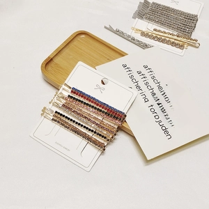 Colorful rhinestone bobby pins set neatly arranged on display card with warm lighting