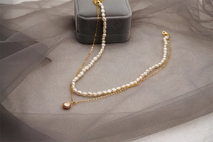 Détail d'un collier de perles d'eau douce double rangée avec chaîne dorée et pendentif