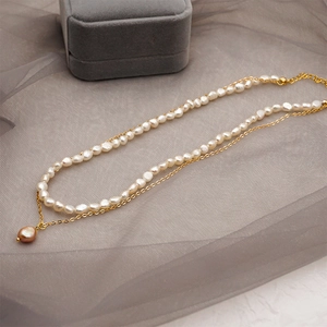 Détail d'un collier double rang en perles d'eau douce baroques avec chaîne dorée et fermoir