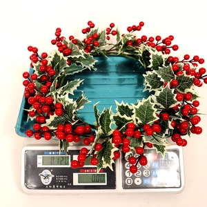 Détail d'une couronne de Noël avec des baies rouges et des feuilles vertes bordées de blanc