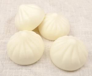 Close-up of four realistic squishy steamed bun toys on a textured fabric background
