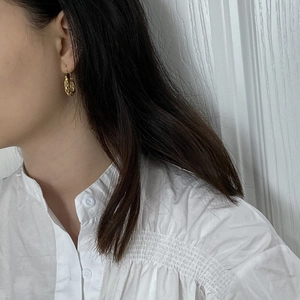 Detail of gold hollow woven hoop earrings on model with minimalist vintage aesthetic