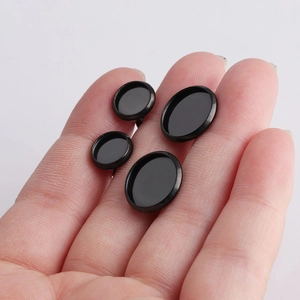 Handheld view of four black stainless steel round bezel trays for DIY earring making