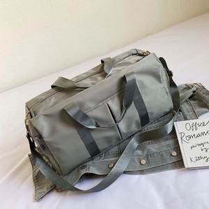 Detail of grey-green nylon travel bag with shoe compartment on denim jacket background