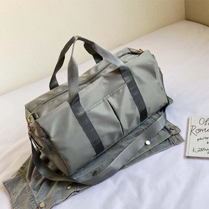 Macro view of gray-green sports duffel bag with front pockets and durable nylon texture