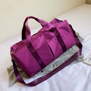 Detail view of purple large capacity nylon fitness bag on white bedding with shoulder strap