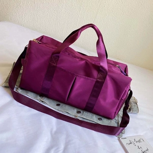 Detail of purple waterproof travel bag with dual handles and adjustable shoulder strap