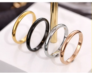 Polished stainless steel rings in gold black silver and rose gold on a minimal stand