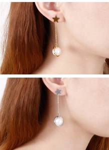 Detailed close-up of gold and silver star earrings with delicate chain and pearl charms