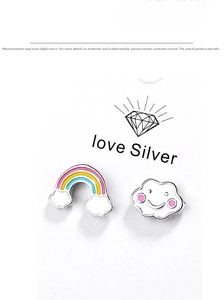 Dettaglio degli orecchini creativi con arcobaleno e nuvola su carta argentata