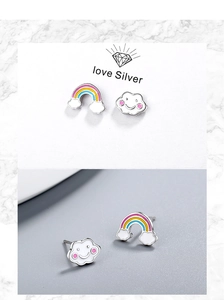 Dettaglio macro di orecchini asimmetrici in smalto con arcobaleno e nuvola felice