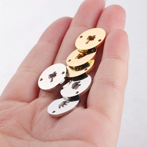 Macro view of gold and silver circular pendants with tree cutout patterns held in hand