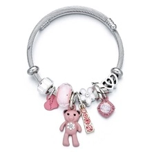 Close-up of silver snake chain bracelet with pink teddy bear and heart charms