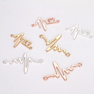 Macro shot of heartbeat wave pendant connectors in gold, silver, and rose gold finishes